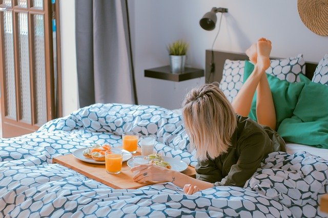Woman lying on bed at home with breakfast tray