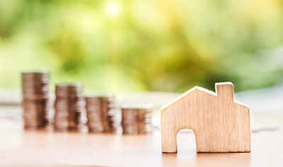 Small wooden house with stack of coins in the background -  Nattanan Kanchanaprat, Pixabay